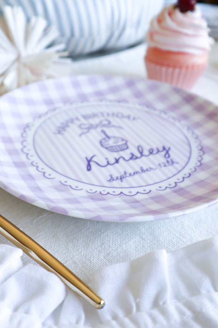Round ceramic plate with Lavender gingham boarder. Happy Birthday with a cupcake in the center. Personalized name and birth date