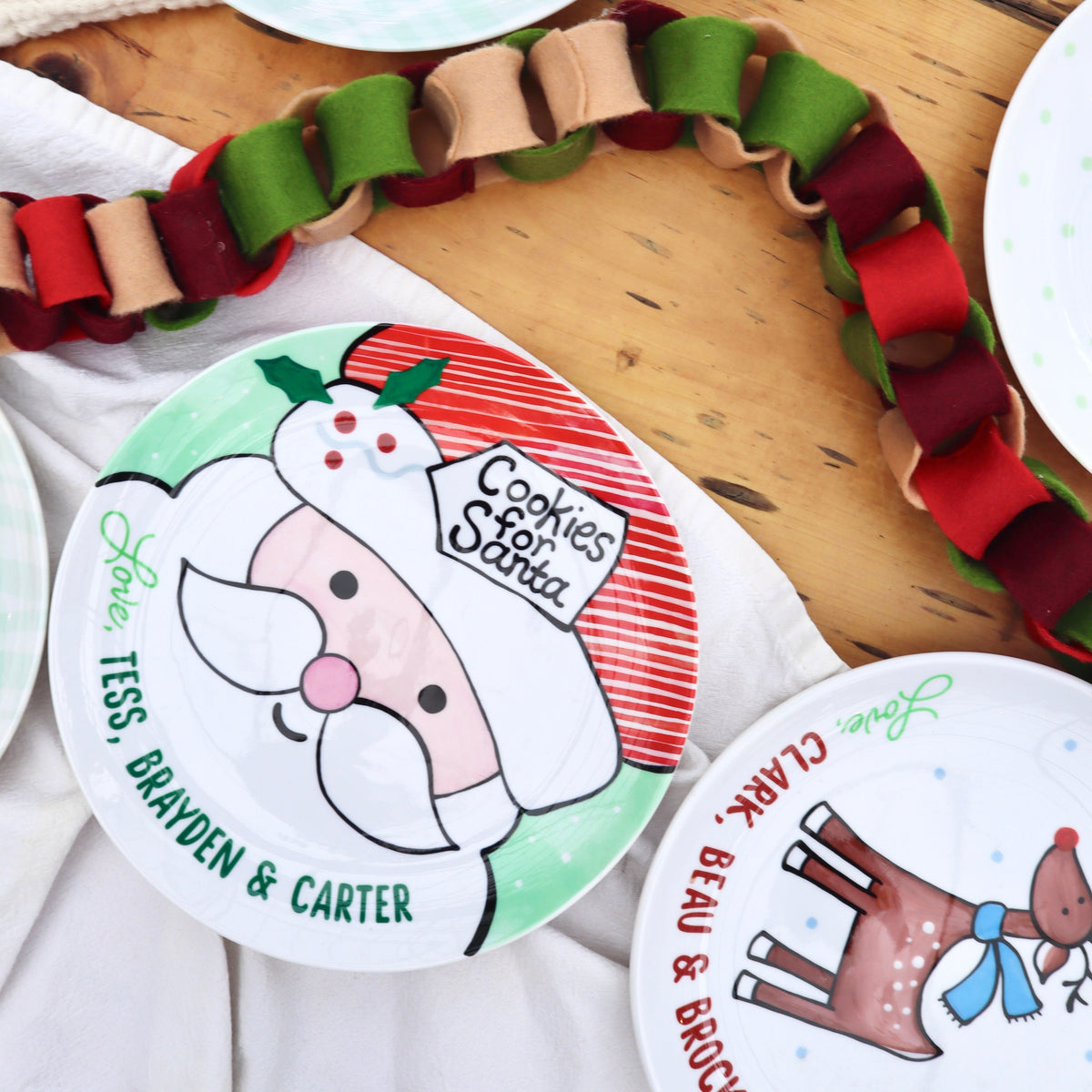 Round ceramic Cookies for Santa plate laid on tale with reindeer plate. Felt paperchain decoration